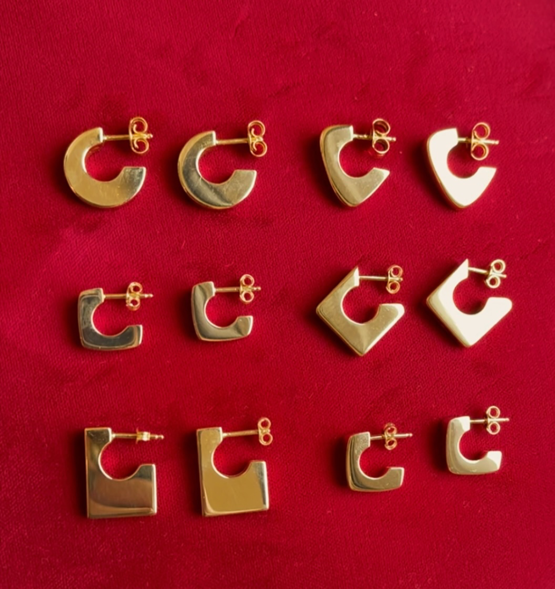 Gold hoop earrings displayed on a red background